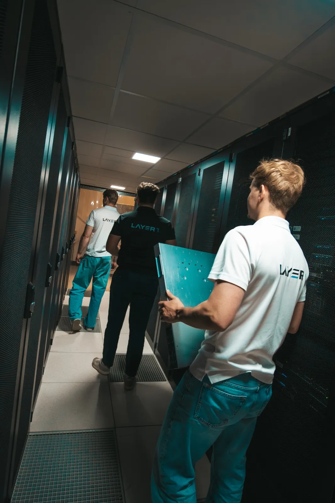 Layer One team carrying server hardware through a datacenter aisle